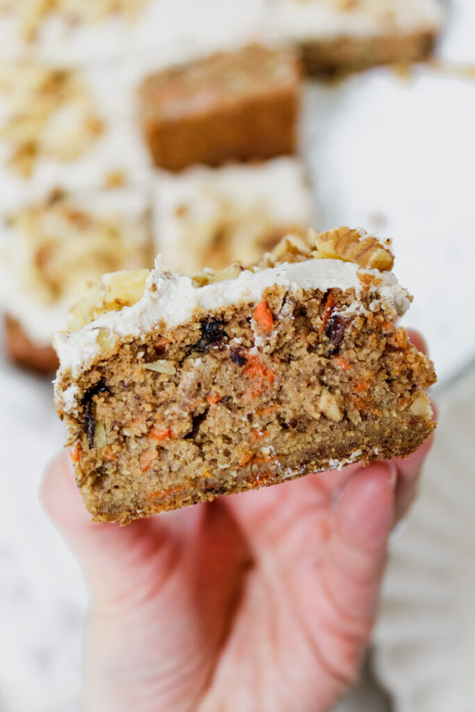 hand holding a slice of the best healthy carrot cake ever