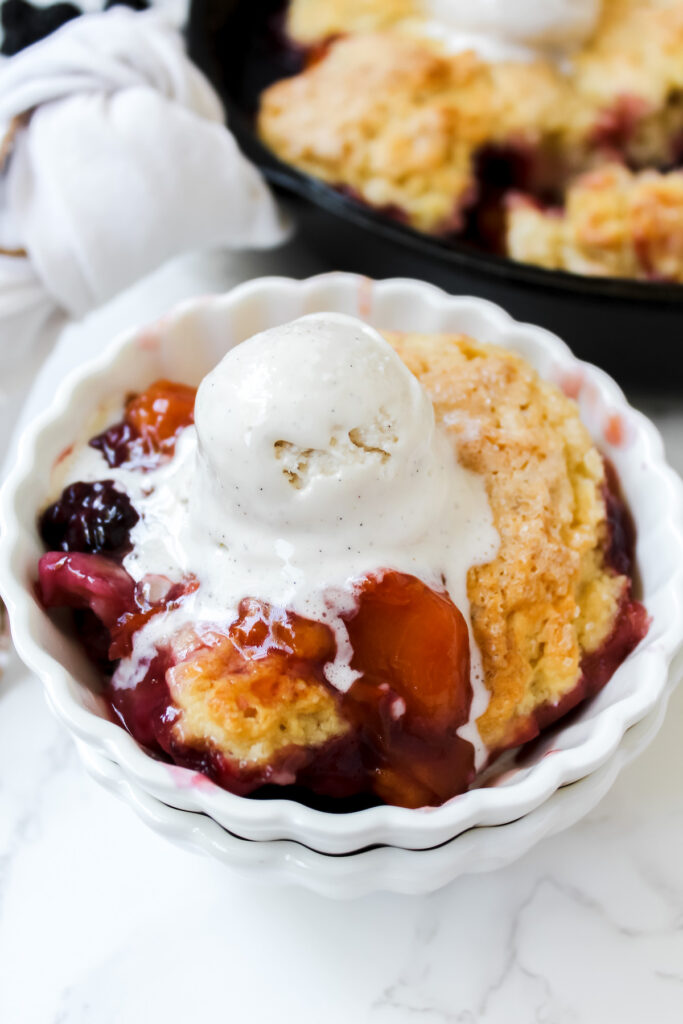 bowl of peach cobbler with a scoop of ice cream