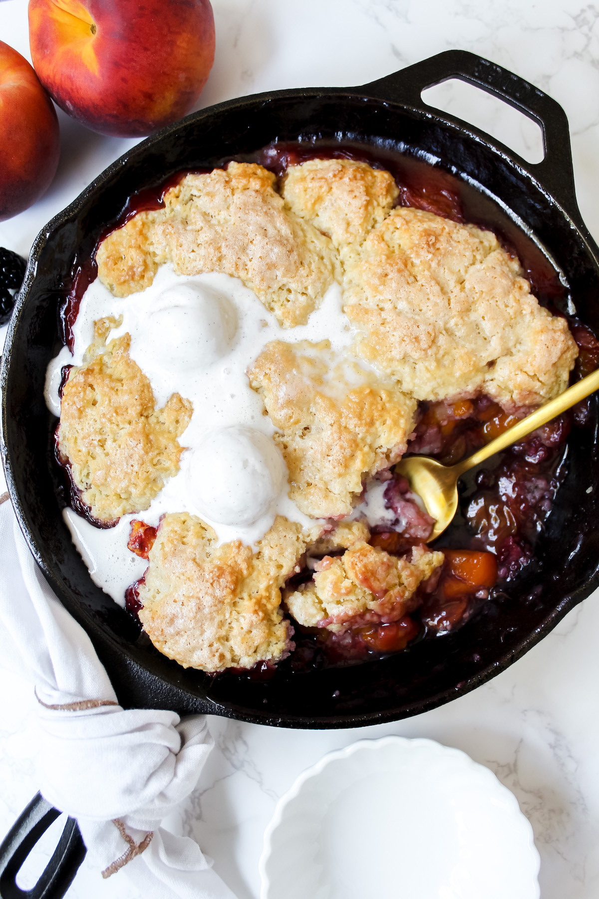 overview shot of vegan blackberry peach cobbler with a scoop taken out