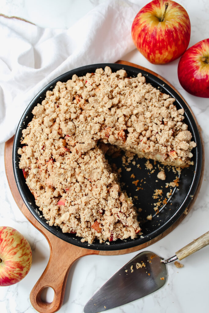 overview shot of entire pan of apple crumb cake with a slice taken out of it