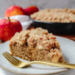 side view shot of a slice of apple crumb cake on a plate with a fork