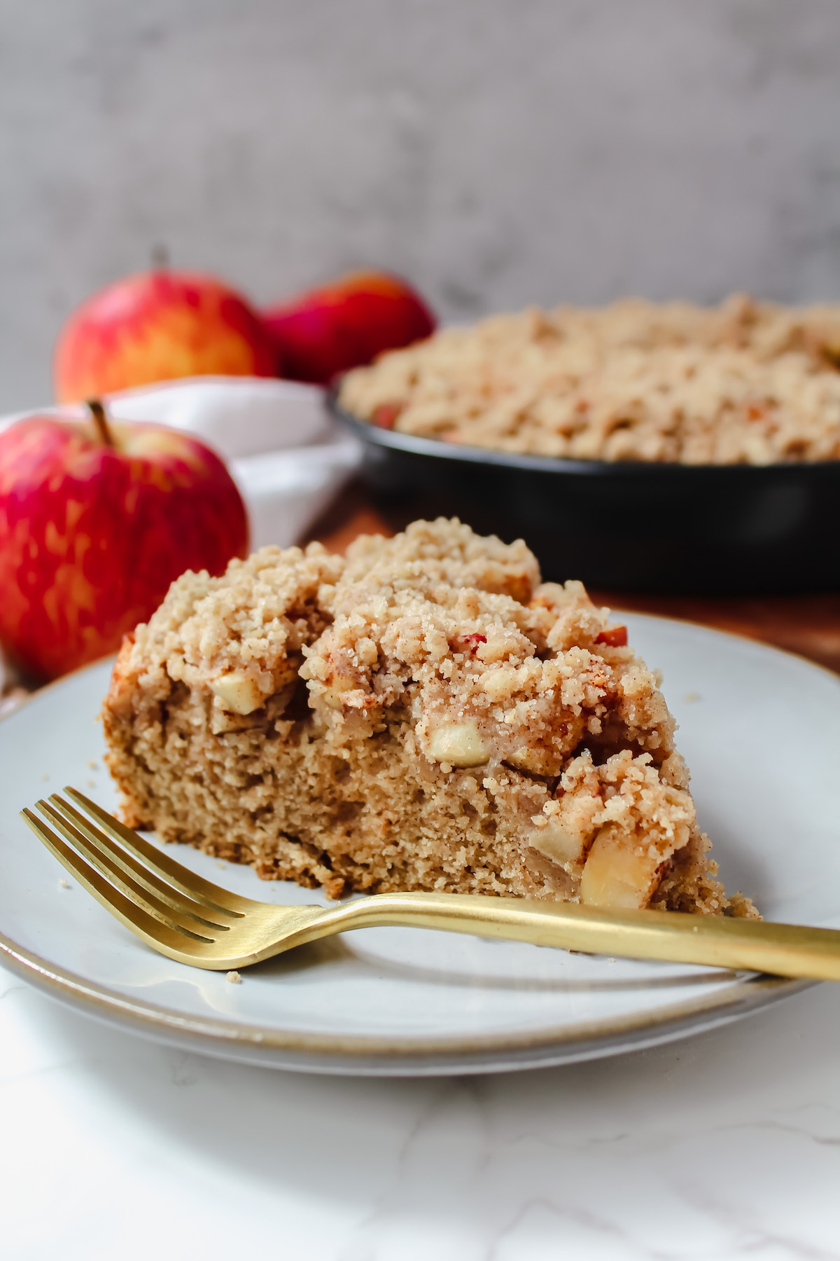 side view shot of a slice of apple crumb cake on a plate with a fork