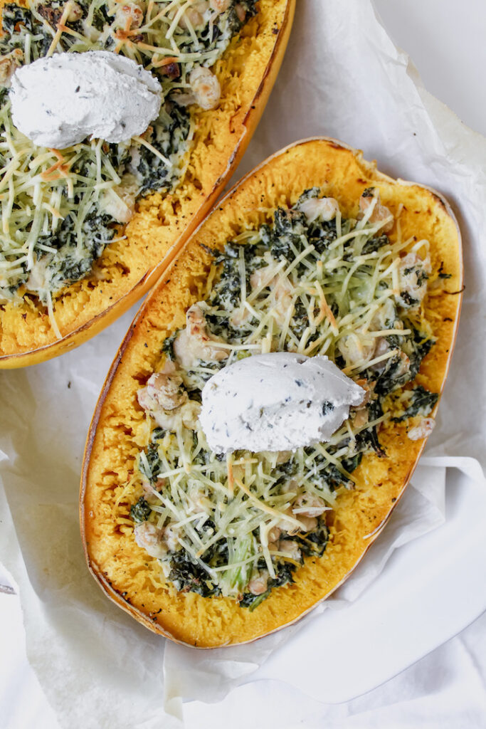 overview shot of creamy white bean and kale stuffed spaghetti squash with a dollop of cream cheese on top