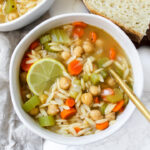 overview shot of bowl of orzo soup with bread on the side