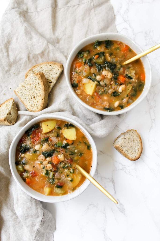 two bowls of soup with bread on the side