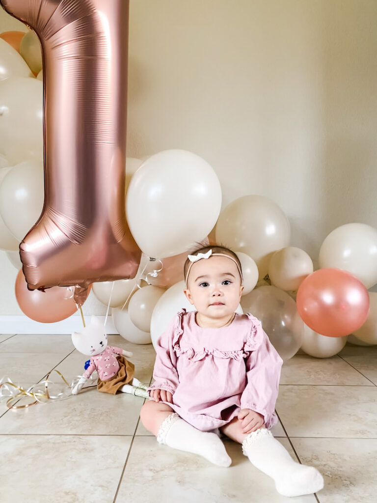 Sophie sitting with her birthday balloons and a number one balloon