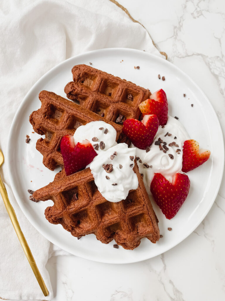 overview shot of entire plate of waffles with yogurt, cacao nibs, and strawberries on top