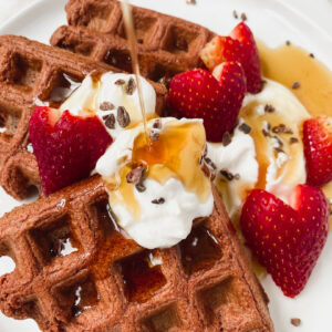 pour shot of maple syrup over waffles