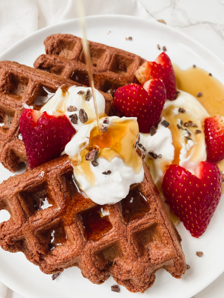 pour shot of maple syrup over waffles