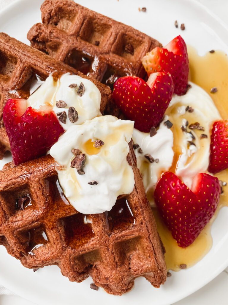 close up of waffles with maple syrup, yogurt, and strawberries