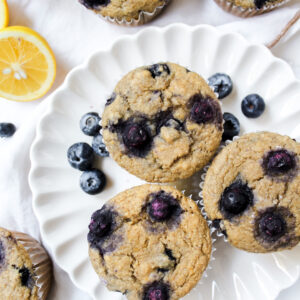 lemon blueberry muffins on a plate with sliced lemons on the side