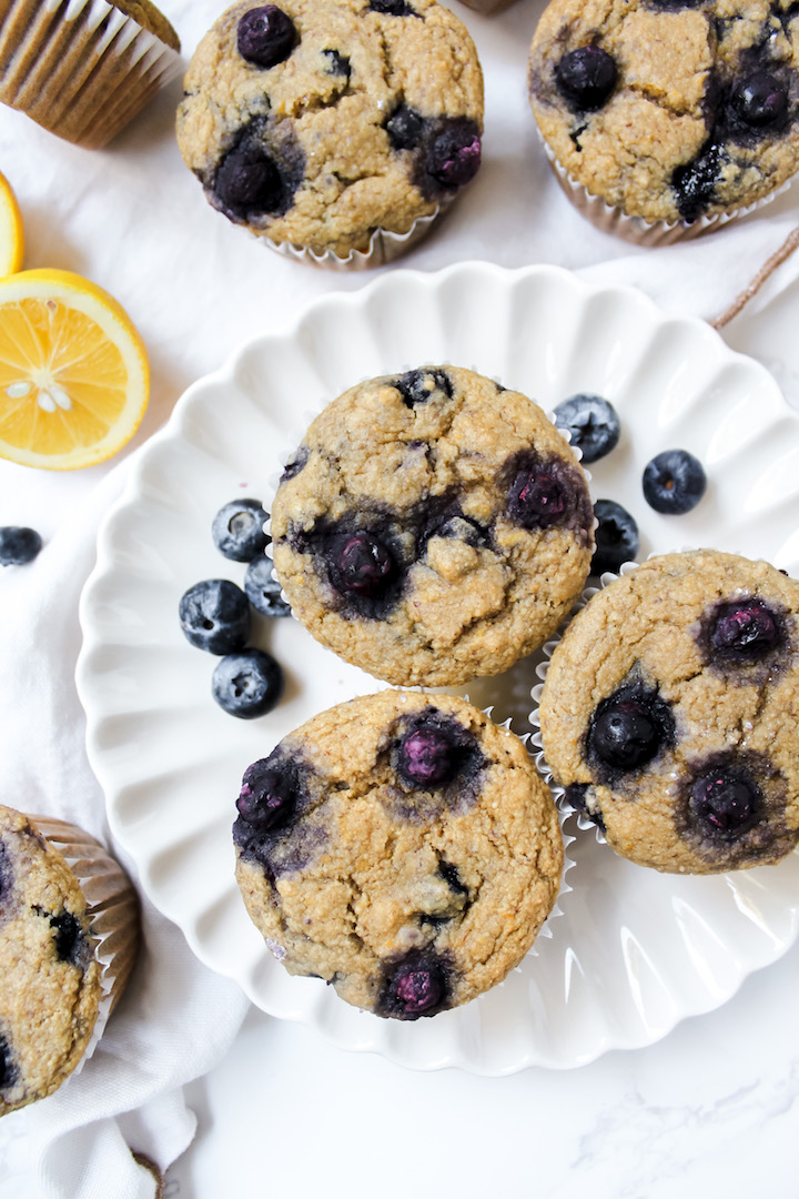 lemon blueberry muffins on a plate with sliced lemons on the side