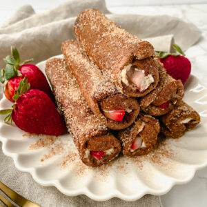 a stack of strawberry cheesecake french toast roll ups on a plate with strawberries
