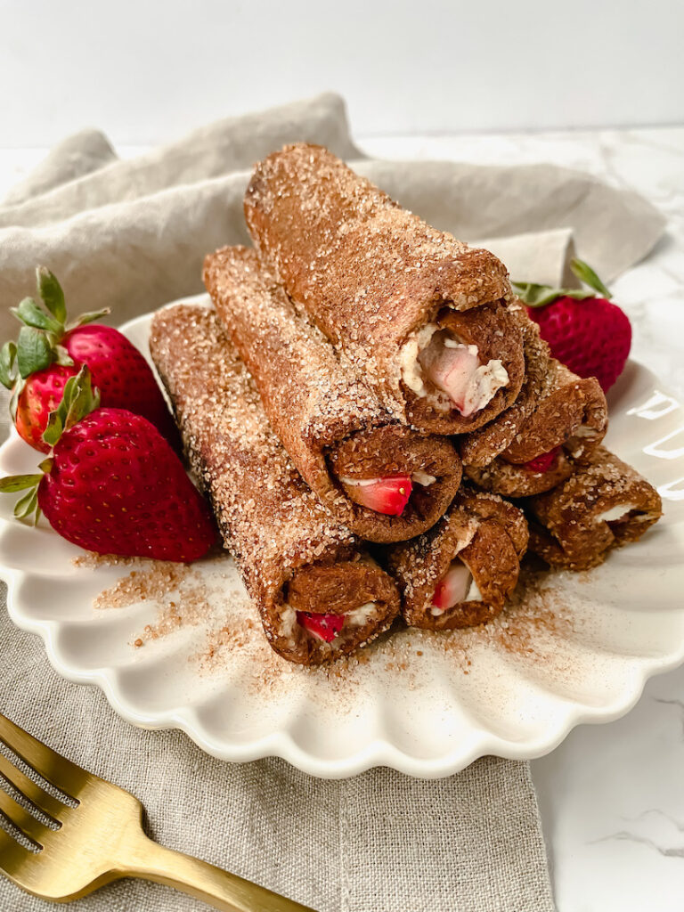 a stack of strawberry cheesecake french toast roll ups on a plate with strawberries