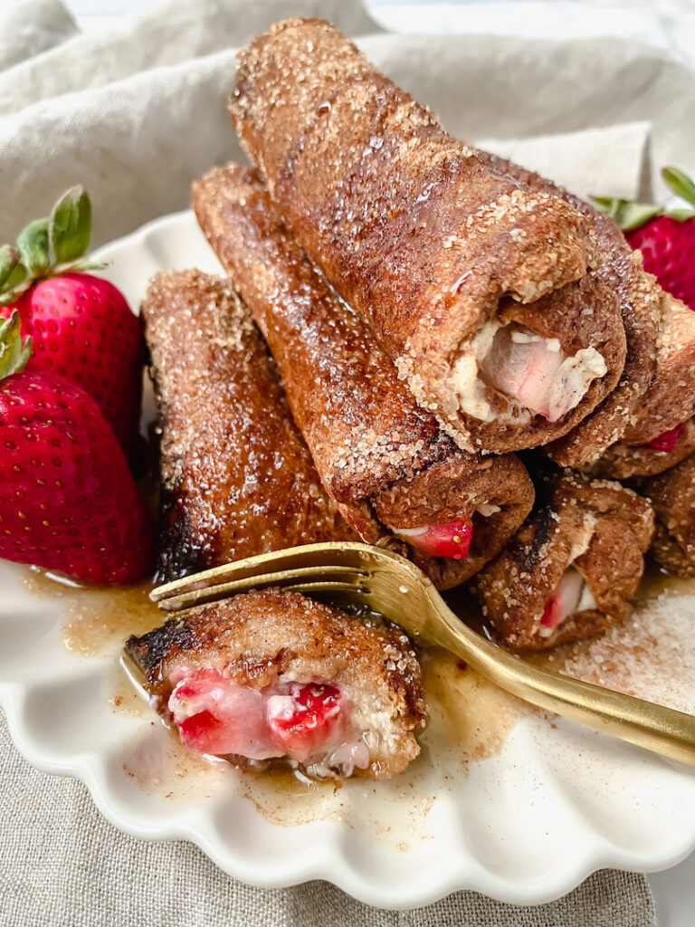 Fork cut into one strawberry cheesecake french toast roll up
