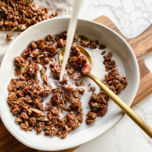 overview shot of almond milk being poured into a bowl of granola