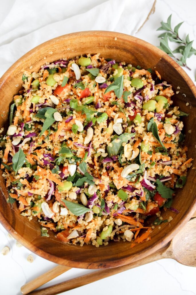 overview shot of wooden bowl with spicy thai peanut quinoa salad