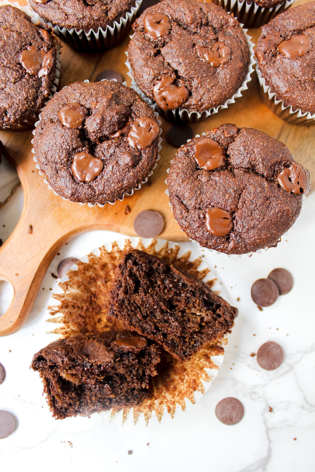 chocolate muffin split in half and whole muffins on a wooden board