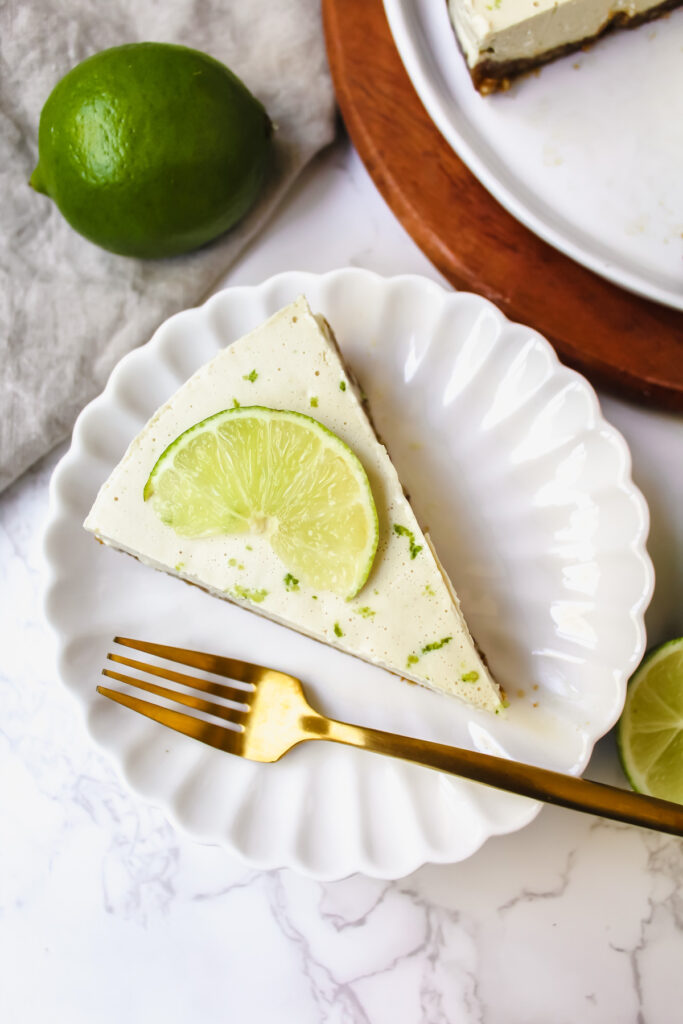 a slice of vegan key lime pie on a plate with a gold fork on the side