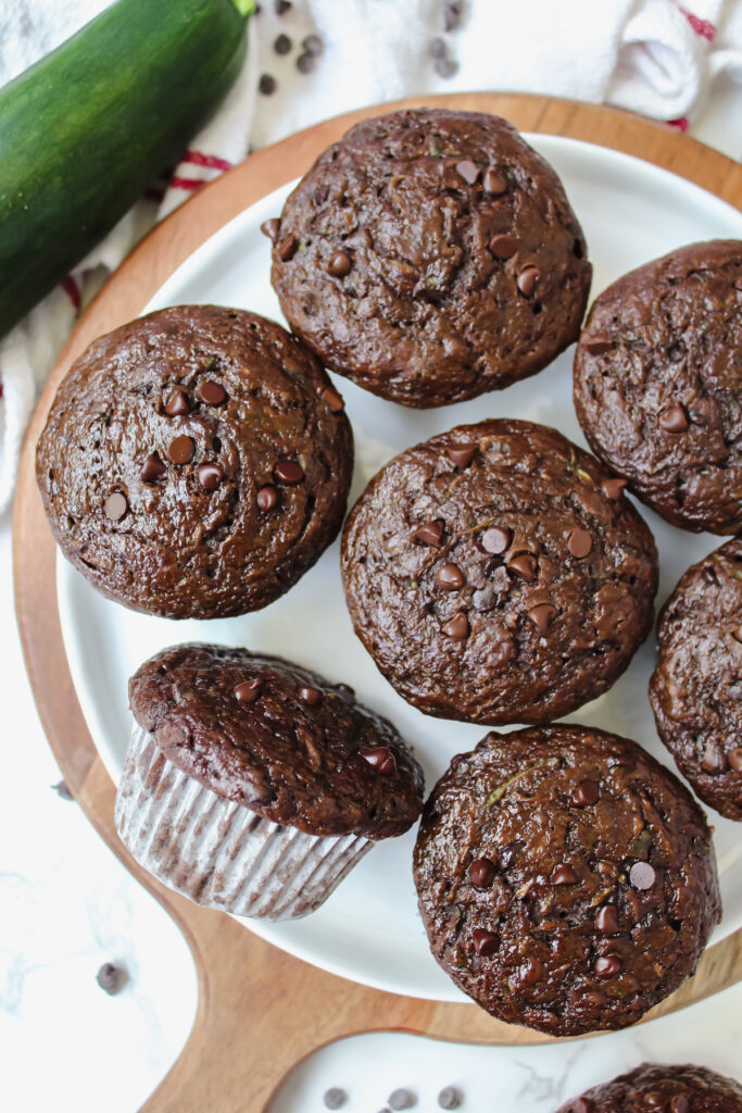 plate of chocolate zucchini muffins with one muffin on it's side