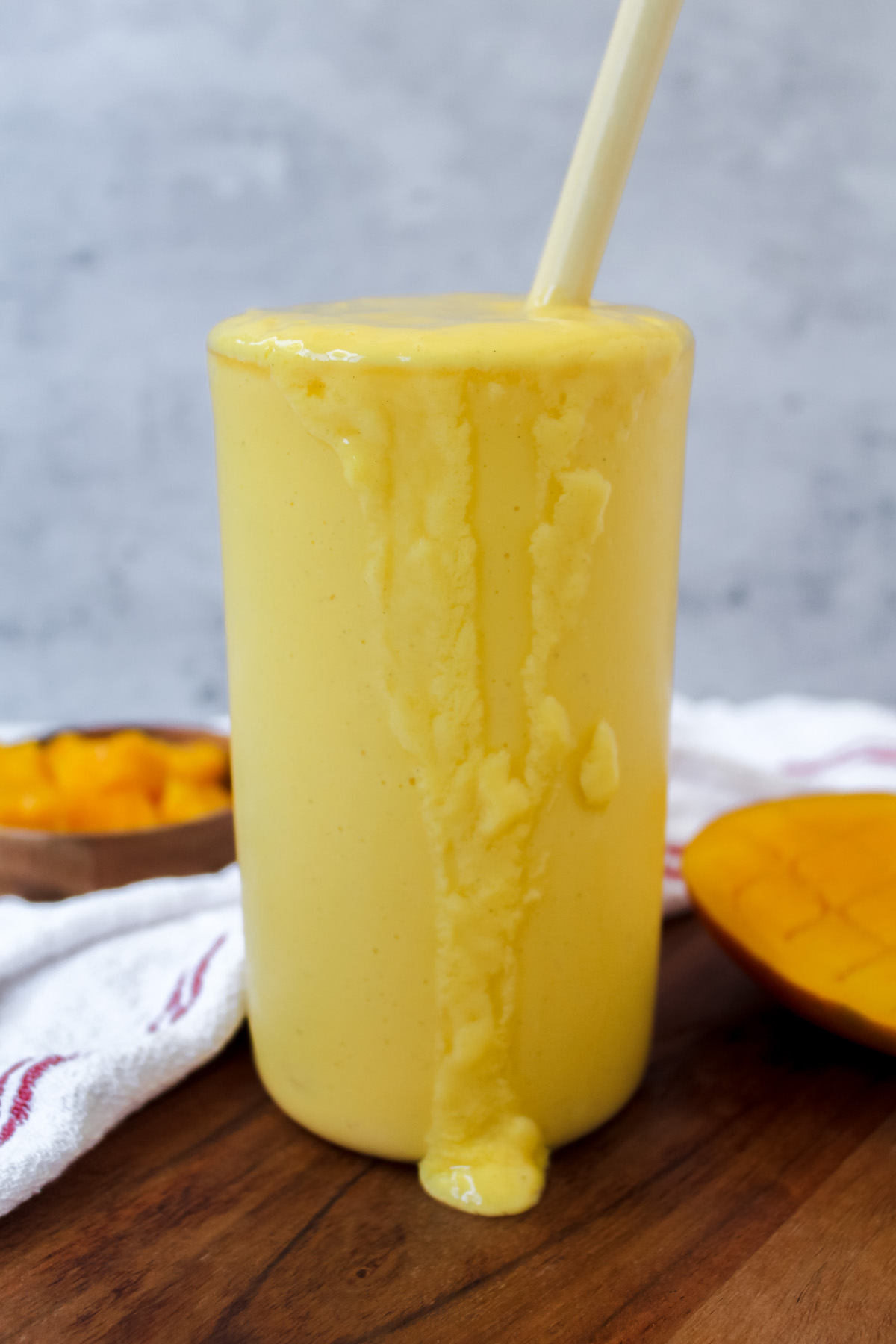 side view of a glass of coconut mango lassi with some dripping down the side