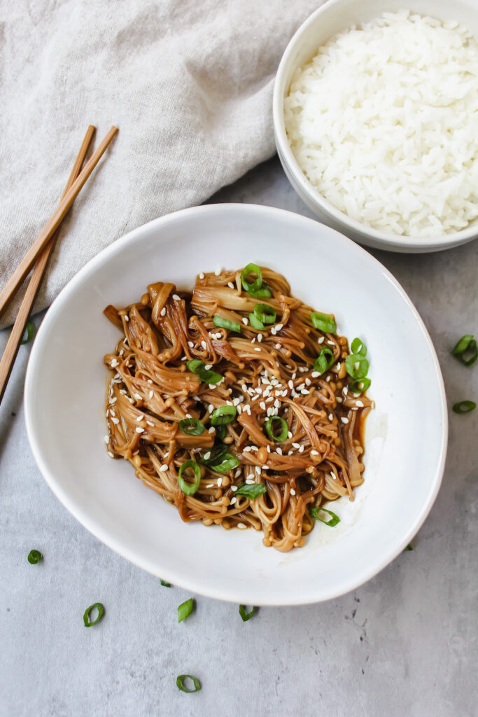 Overview shot of miso soy enoki mushrooms in a bowl with rice on the side