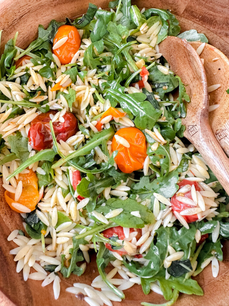 close up of orzo salad in wooden bowl