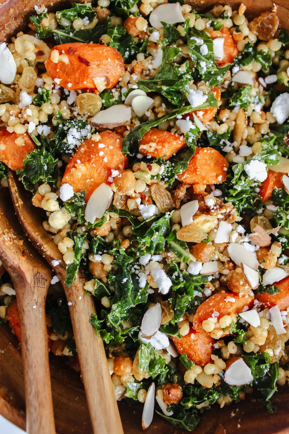 Harissa Roasted Carrots and Chickpeas Couscous Salad in a wooden bowl with wooden spoons