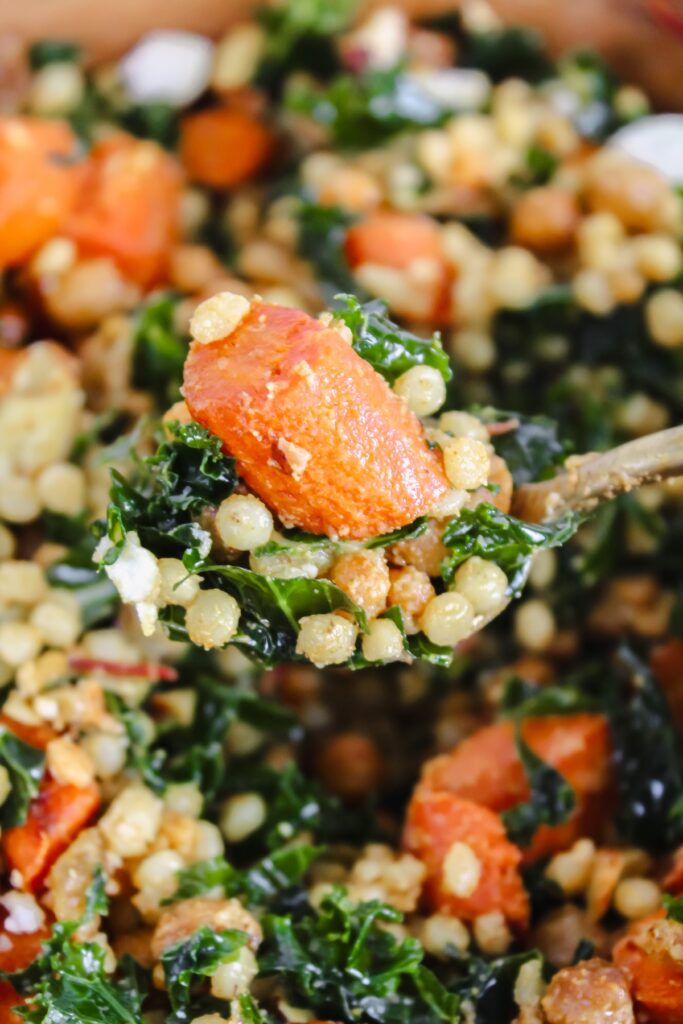 spoon with harissa roasted carrots and chickpeas couscous salad on it
