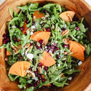 overview shot of persimmon pomegranate arugula salad