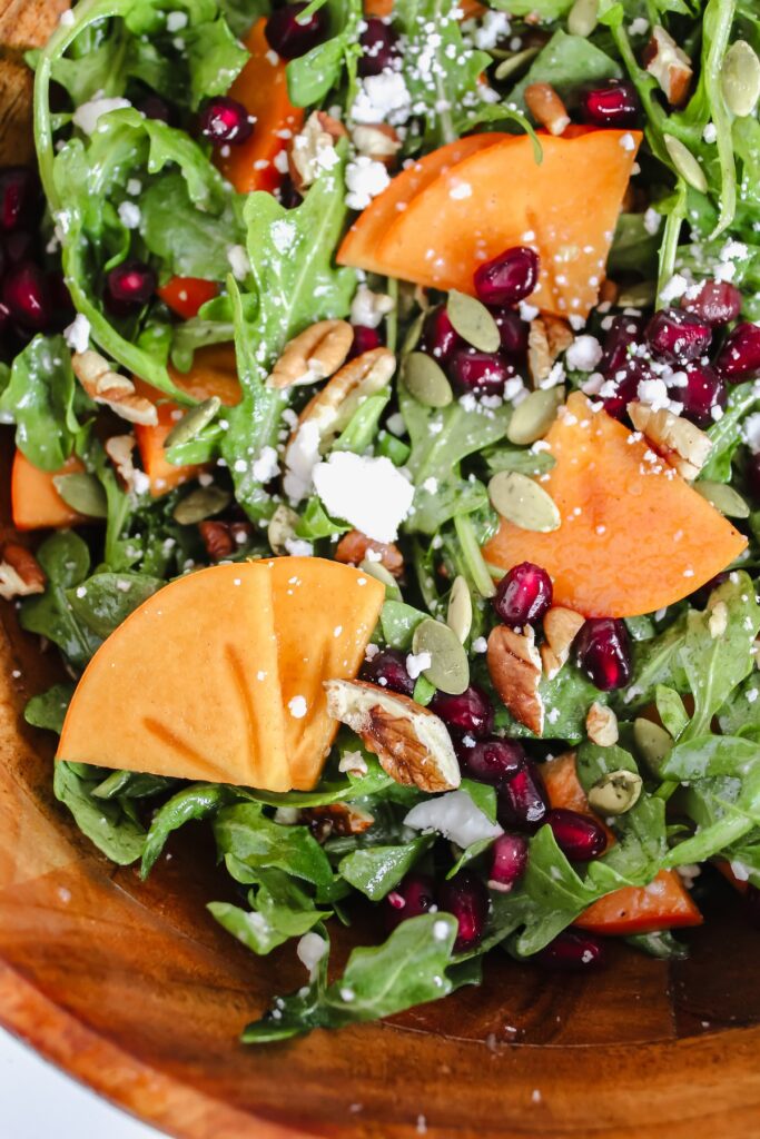 close up shot of persimmon pomegranate arugula salad