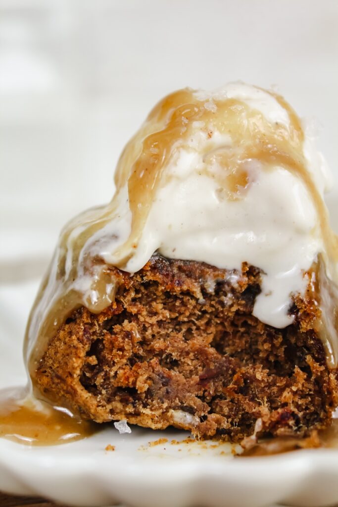 close up shot of sticky toffee pudding with ice cream on top