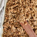 cinnamon toast crunch granola on a baking sheet with wooden spatula
