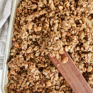 cinnamon toast crunch granola on a baking sheet with wooden spatula