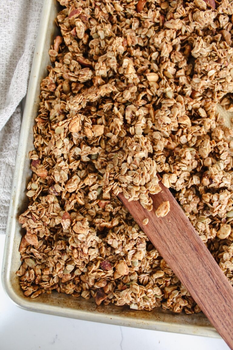 cinnamon toast crunch granola on a baking sheet with wooden spatula