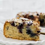angled shot of a slice of blueberry almond croissant cake on a plate