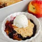 close up shot of cobbler in a white bowl with ice cream on top