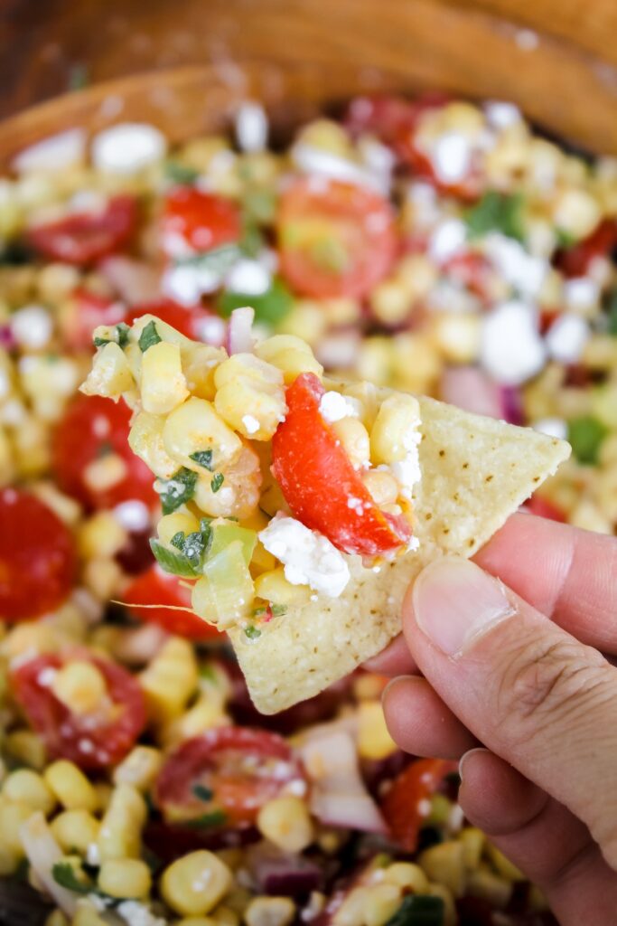 tortilla chip with tomato corn feta salad on it