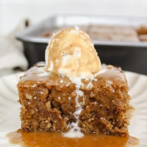 a slice of banana sticky toffee pudding on a plate with ice cream on top