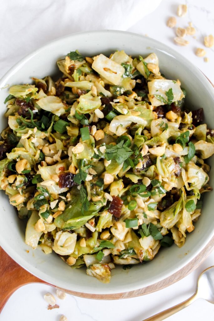 overview shot of roasted cabbage peanut date salad in a white bowl