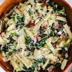 overview shot of spinach artichoke pasta salad in a wooden bowl