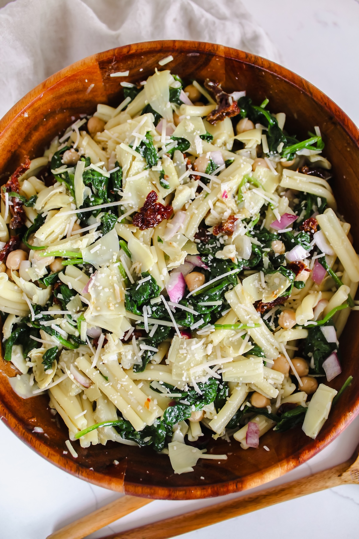 overview shot of spinach artichoke pasta salad in a wooden bowl