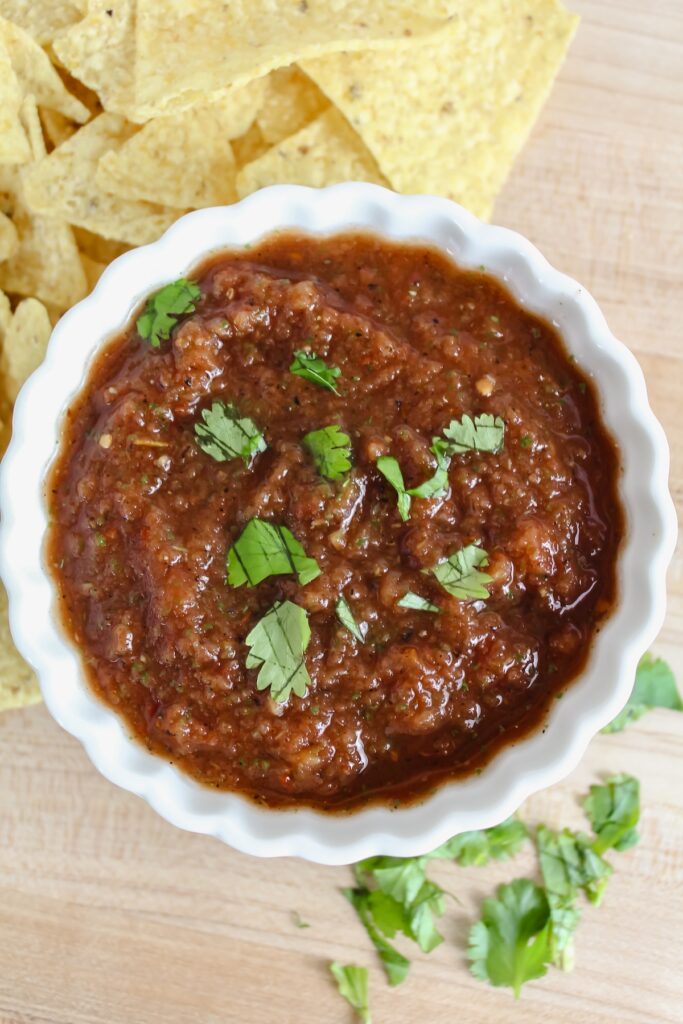overview shot of a white bowl with easy blender salsa in it and chips on the side