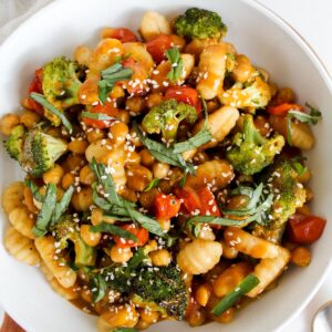 overview shot of bowl of sheet pan gnocchi and veggies with sauce on top