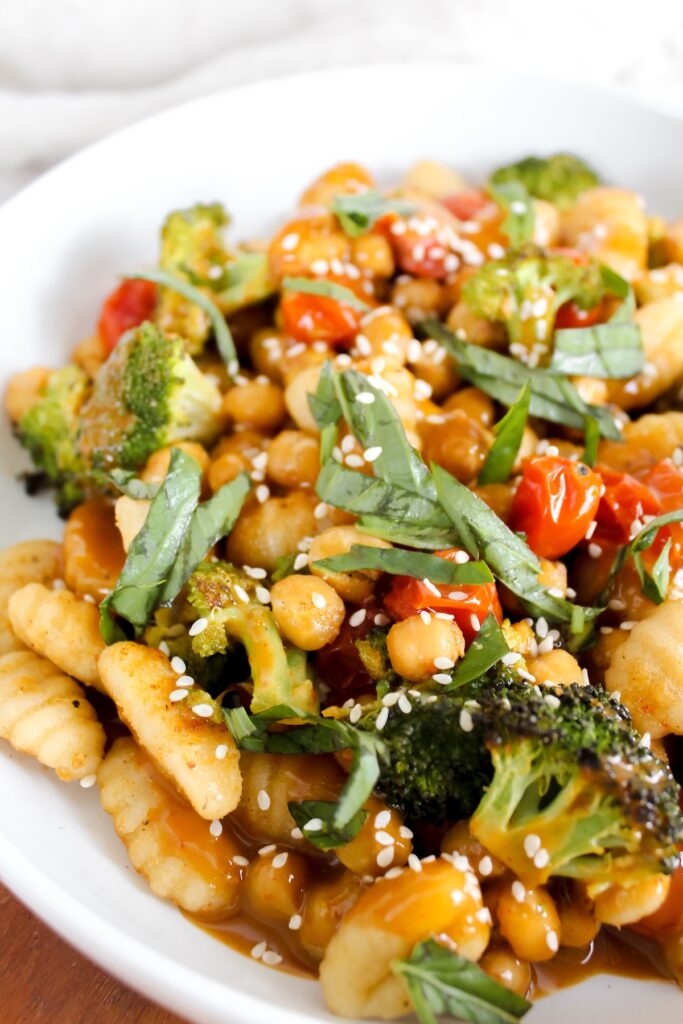 angled shot of sheet pan gnocchi and veggies in a white bowl